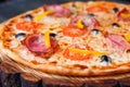 Close up of tasty sicilian pizza with bacon, olives and tomatoes