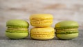 Close up of tasty stacked yellow and green macaron cakes on grey table. Pistachio and lemon french macaroons