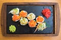 Close up of tasty wooden tray of sushi on a black plate standing on a wooden table in a Japanese restaurant Royalty Free Stock Photo