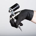 Close-up of Tattooist hands in black gloves with tattoo machine