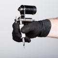 Close-up of Tattooist hands in black gloves with tattoo machine