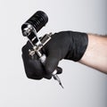 Close-up of Tattooist hands in black gloves with tattoo machine