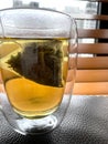 Close-up of tea in double walled glass with blinds background