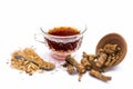 Close up of tea of Indian sarsaparilla or nnanari in a glass cup along with raw sarsaparilla and its powder.