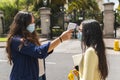 Close-up of a teacher measuring the temperature of a Latina teenage student at the entrance to classes for covid prevention.