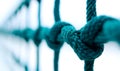 Close-up of teal colored ropes with knots. Focus on interconnected rope network. Background is a white plane. Potential use for Royalty Free Stock Photo