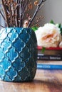 Close up of teal moroccan vase with sticks and background decor