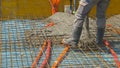 CLOSE UP: Team of builders pours a concrete slab over the reinforced metal mesh.