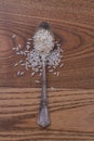 Close up teaspoon with rice on wooden table.