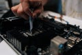 Close-up of technician hand meticulously applying thermal paste to CPU of computer motherboard, demonstrating process of Royalty Free Stock Photo