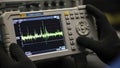 Closeup of a technician holding a portable spectrum analyzer displaying waveform data Royalty Free Stock Photo