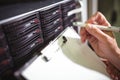 Close-up of technician maintaining record of rack mounted server on clipboard