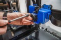 Close-up of technician's hands doing maintenance on 3D printer