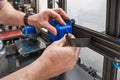 Close-up of technician's hands doing maintenance on 3D printer