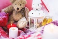 A close-up of a teddy bear with Christmas candles on a cozy checkered plaid outdoors next to a red gift box sprinkled