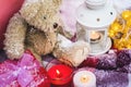 A close-up of a teddy bear with Christmas candles on a cozy checkered plaid outdoors next to a red gift box sprinkled