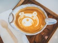 Close-up teddy bear latte art coffee in handmade ceramic cup on wooden tray on white background Royalty Free Stock Photo