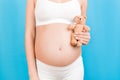 Close up of teddy bear in pregnant womans hand at blue background. Future mother is wearing white underwear. Nacked belly.