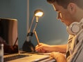 CLOSE-UP OF TEEN TAKING NOTES IN A DIARY AT HIS DESK Royalty Free Stock Photo