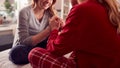 Close Up Of Teenage Daughter In Pyjamas Sitting On Bed Talking With Mother In Bedroom Holding Hands Royalty Free Stock Photo