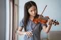 Close up of teenage girl learn to play a violin instrument beside the window