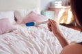 Close Up Of Teenage Girl Sitting On Bed At Home Looking At Positive Pregnancy Test Royalty Free Stock Photo