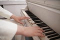 Close up of teenager arms with old white grand piano. person in white clothes plays music.