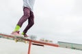 A close-up of a teenager`s leg of a skateboarder glides on a skateboard along the railing in the skatepark. The concept