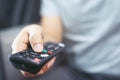 Close up Television remote control in casual man hands pointing to tv set and turning it on or off. Royalty Free Stock Photo