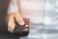 Close up Television remote control in casual man hands pointing to tv set and turning it on or off. select channel watching tv Royalty Free Stock Photo