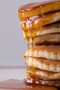 Close-up of tempting stacked pancakes with dripping syrup against gray background