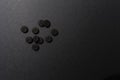 Close up of ten black round pills absorbent carbon lay on a rough grey surface