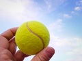 Close-up of  tennis ball in a man  hand agains blue sky Royalty Free Stock Photo