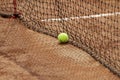 Close up tennis ball and net on court. Close up of tennis ball on clay court. Red clay court Royalty Free Stock Photo