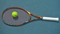 Close up of a tennis racket and a ball resting on the surface of a tennis court