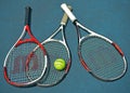 Close up of a tennis rackets and a ball resting on the surface of a tennis court