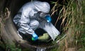 Close-up, the terrorist in a protective suit and gloves, pours liquid with poison, for infection, in a drainpipe