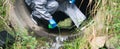 Close-up, a terrorist in a protective suit, pours a liquid with poison, for infection, in the drain pipe