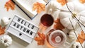 Close-up text board with inscription Hello Autumn,cup of tea, teapot,book,pumpkins,orange maple leaves,twigs on white background, Royalty Free Stock Photo