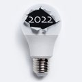 Close-up of text of 2022 inside torn hole on light bulb, on white background. Royalty Free Stock Photo