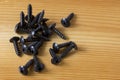 Close up texture of black metal screws pile, black iron screws on a wooden table