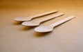 Close-up texture of ecological disposable wooden spoons of natural light color, on harmonious craft paper.