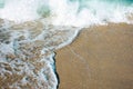 Close up texture of the sea wave rolling on to the golden sandy beach