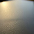A close-up of a textured surface, likely metal, is illuminated by warm, soft sunlight. The light Royalty Free Stock Photo