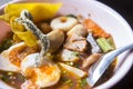 Close up of thai pink noodles soup with half sliced of boiled egg and bbq red pork, fried skin fish, fish balls and morning glory