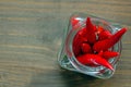 Close up of Thai red fresh hot chilli peppers in a glass vintage jar, blurred brown background. Food pattern. Popular spices