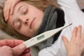 Close-up thermometer. Mother measuring temperature of her ill kid. Sick child with high fever laying in bed and mother holding the Royalty Free Stock Photo