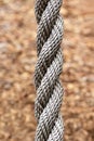 Close up of a thick grey rope outdoor against the ground background