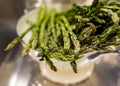 Close up of thin asparagus resting on white colander after being washed