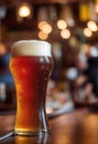 Close up of a thin glass of beer with blurred background on a table with reflection Royalty Free Stock Photo